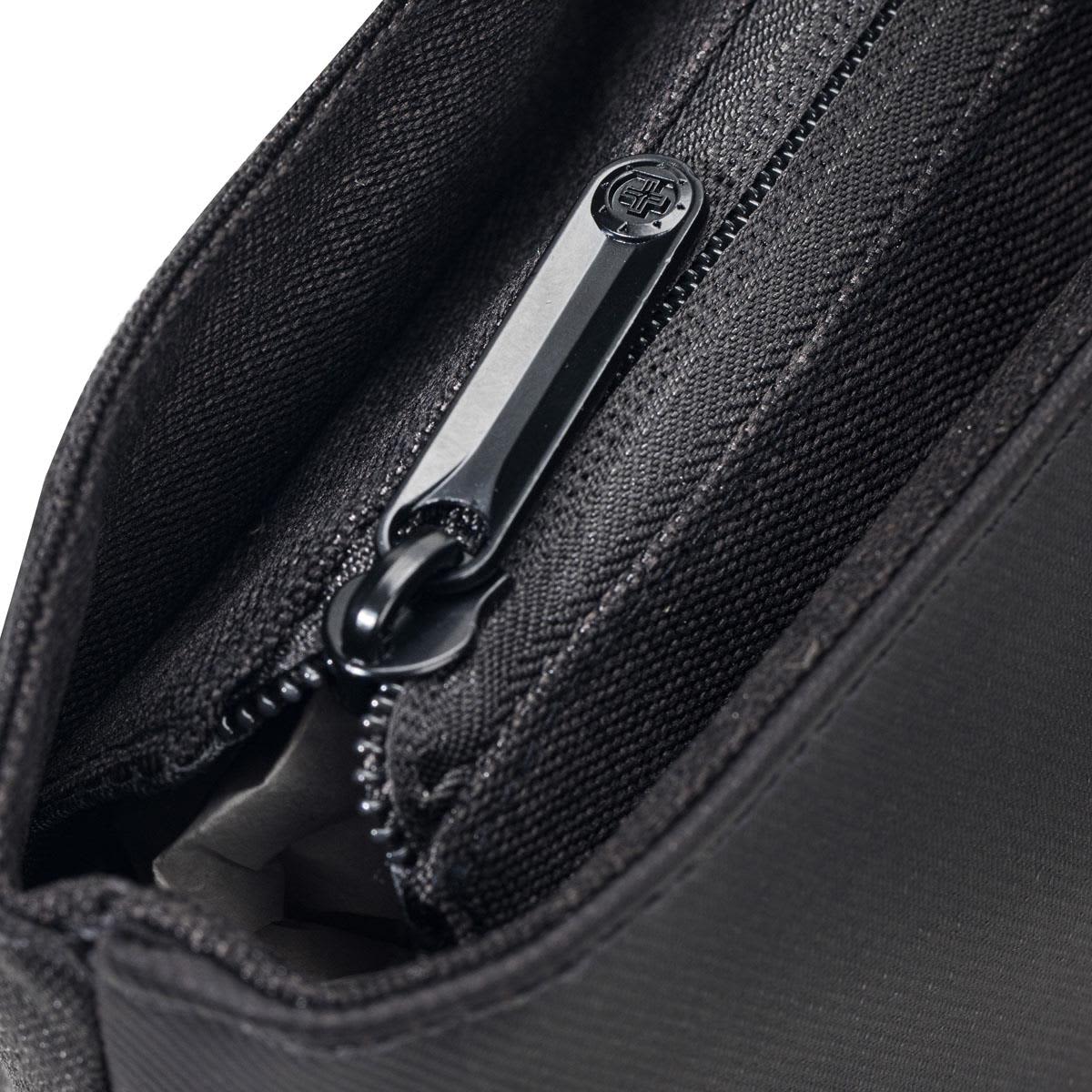 A close-up of a black tote bag's zippered pocket, showcasing its fabric texture and zipper details.