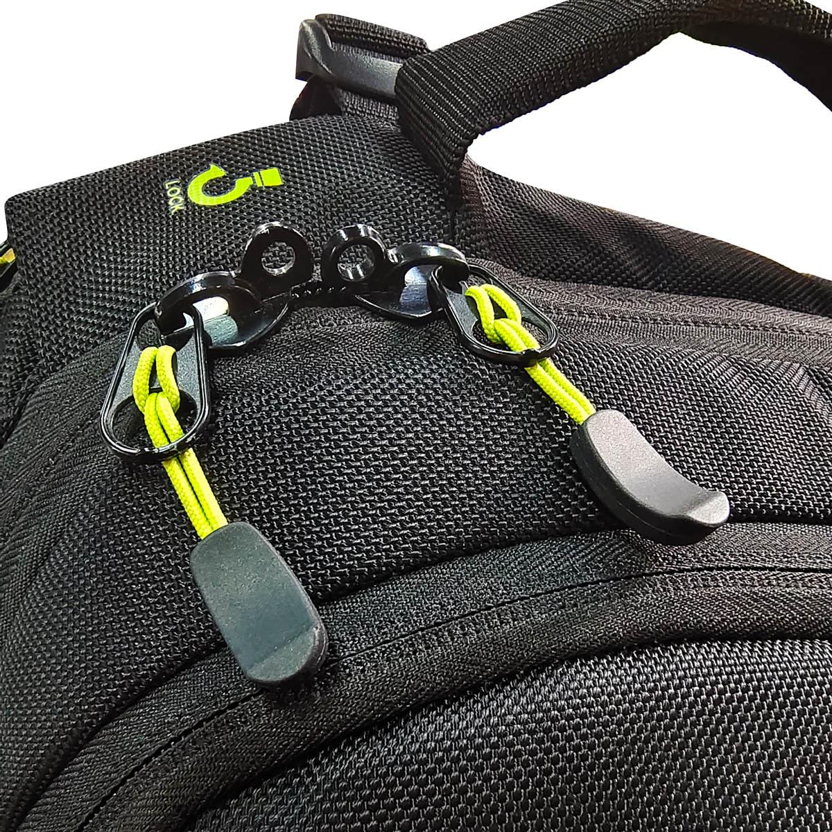 A close-up of a black backpack featuring green accents and a clip with elastic toggles. The bag has branding.