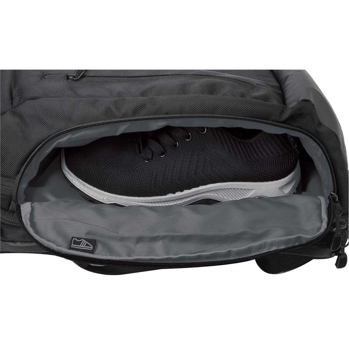 A black backpack featuring a grey compartment with a pair of black and white athletic shoes partially visible inside.