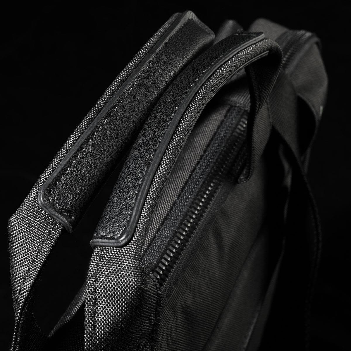 A black laptop sleeve with textured fabric and zipped closure, featuring sturdy handles for carrying.