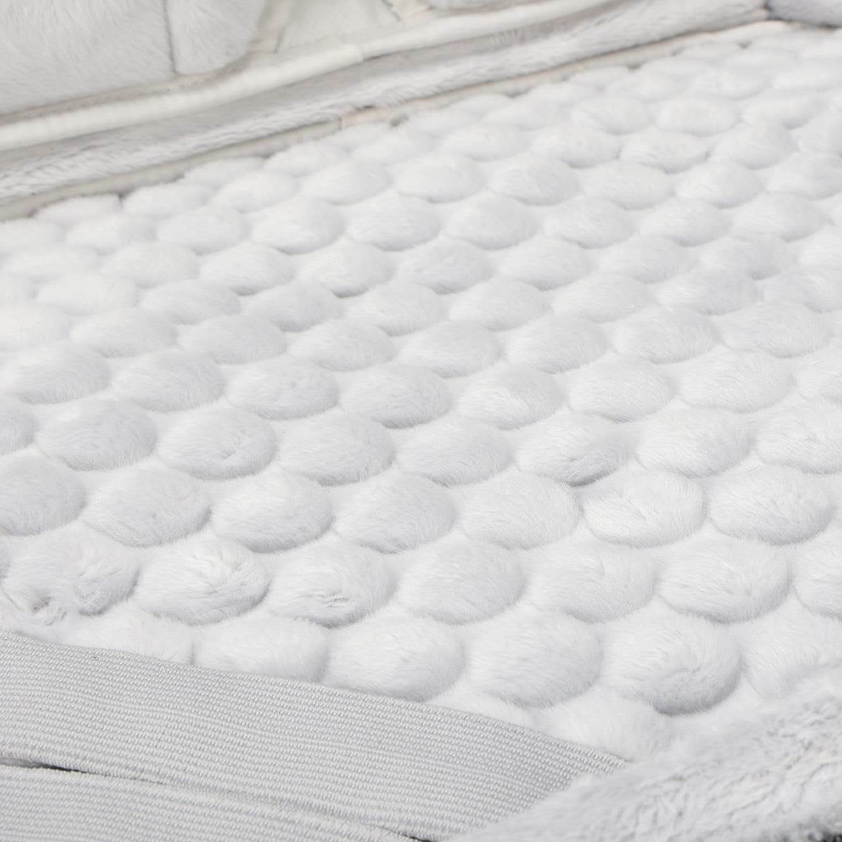 A soft, textured surface featuring white fluffy material with raised round patterns.