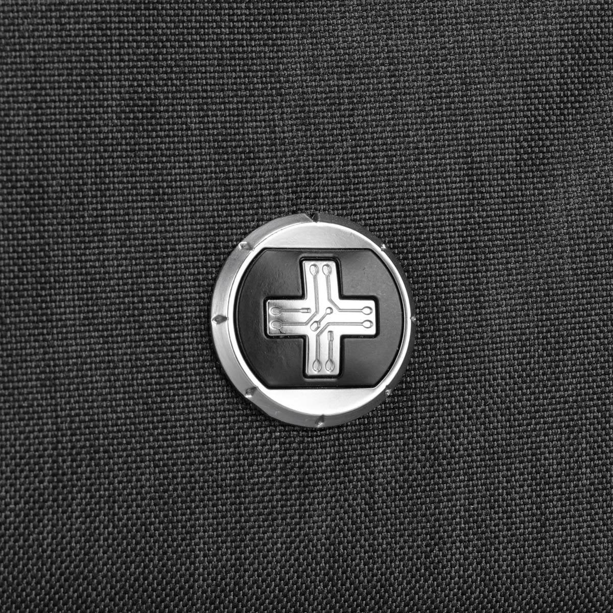 A close-up of a circular logo on a textured black fabric, featuring a distinctive design.