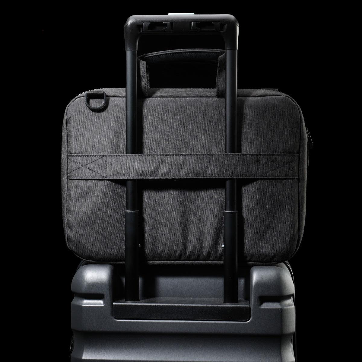 A black laptop sleeve with a handle, designed to fit securely on a suitcase's extendable handle.
