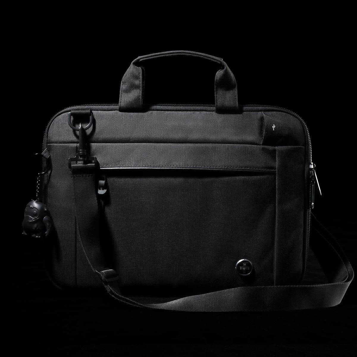 A black laptop sleeve with a handle and adjustable strap, featuring a front pocket and a small attached keychain.