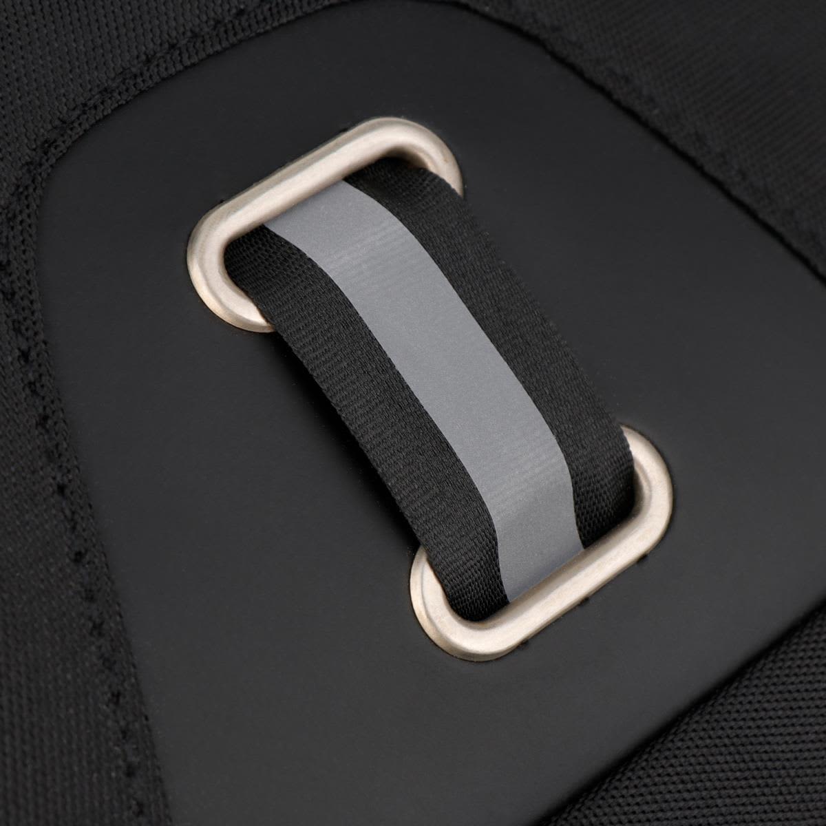 A close-up of a black backpack strap with a grey accent and a metal loop fastening. The backpack has a minimalist design.