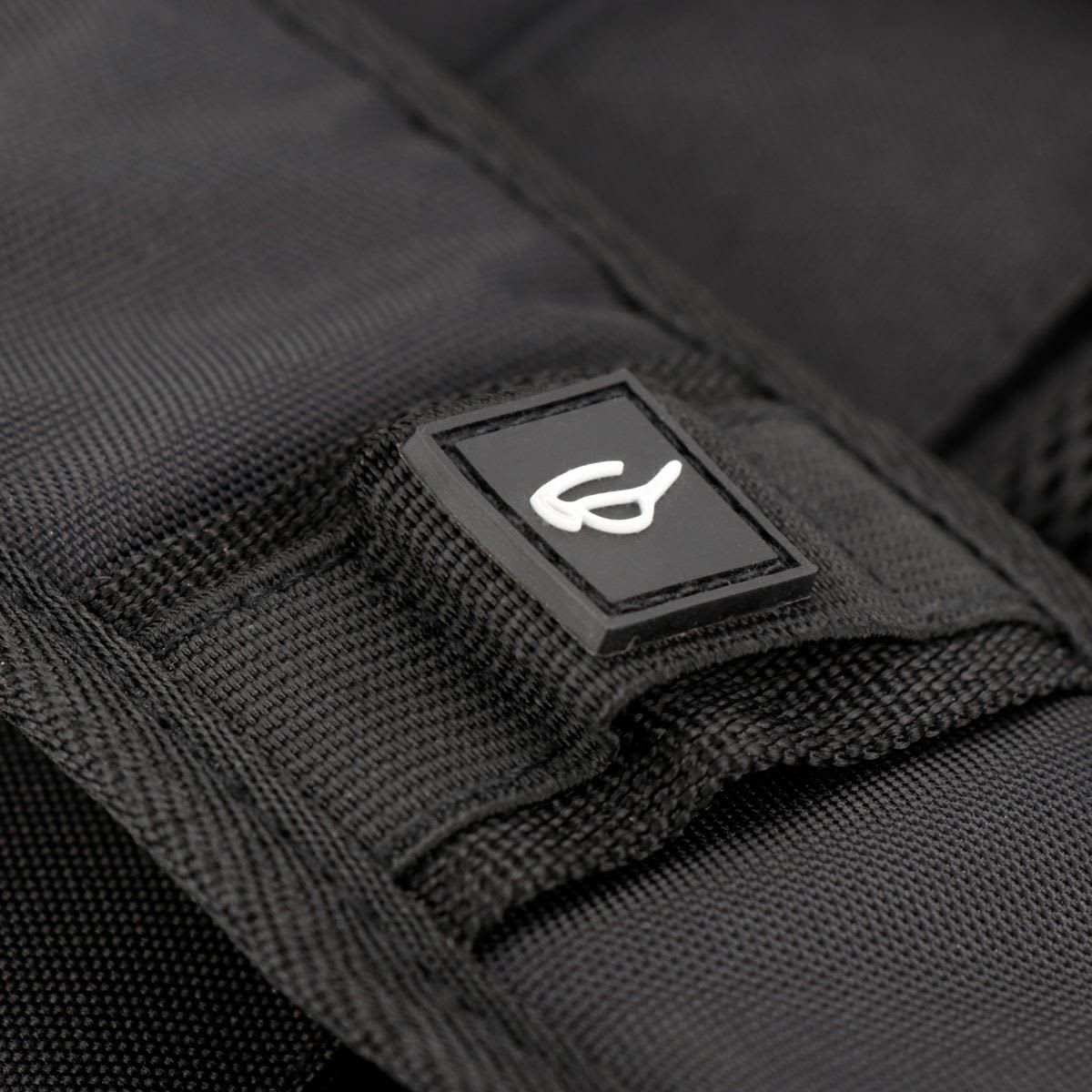 A close-up of a black backpack strap featuring a rectangular logo on the fabric.