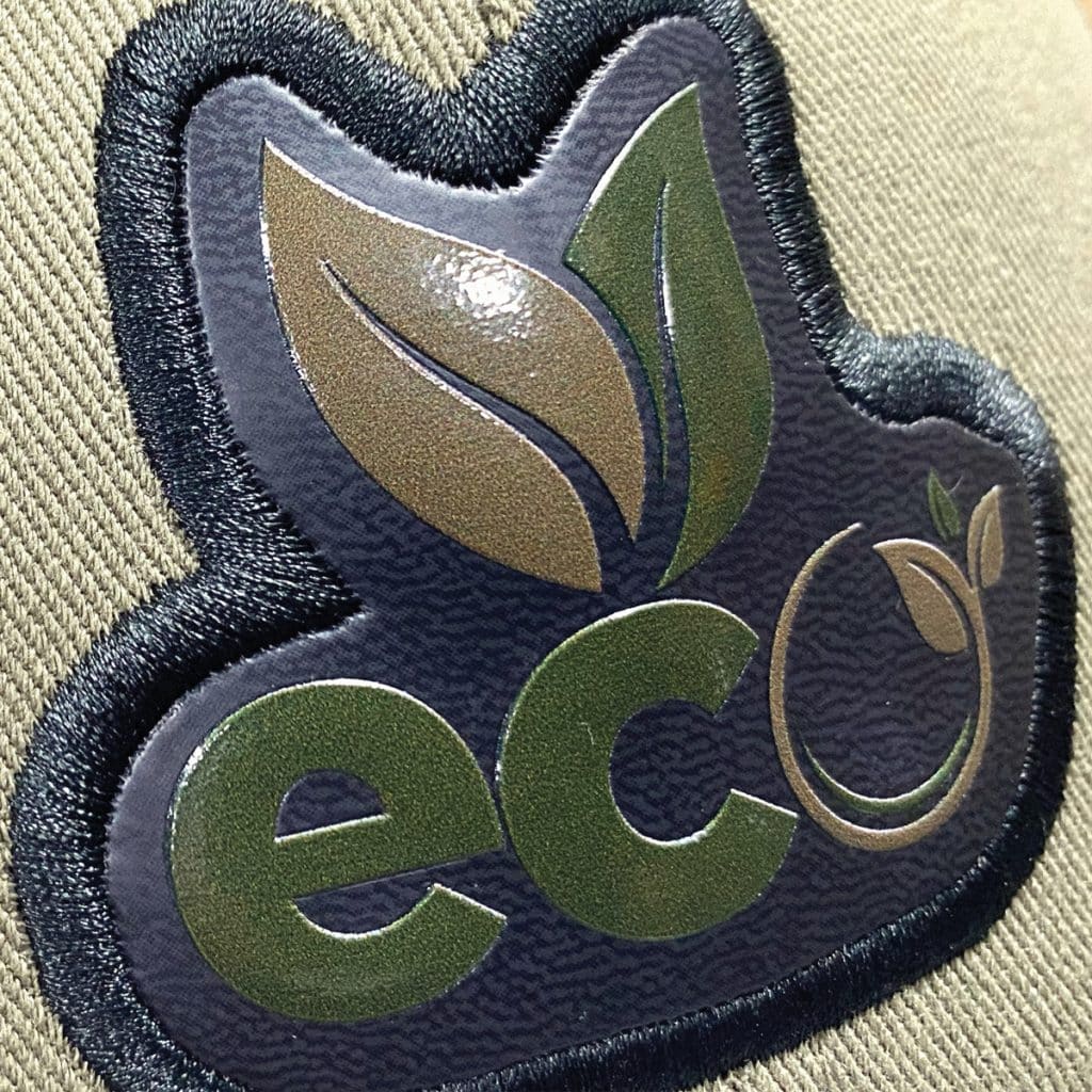 Supaflex badge featuring green eco icon with stitched edge, demonstrating soft texture and full colour detail.