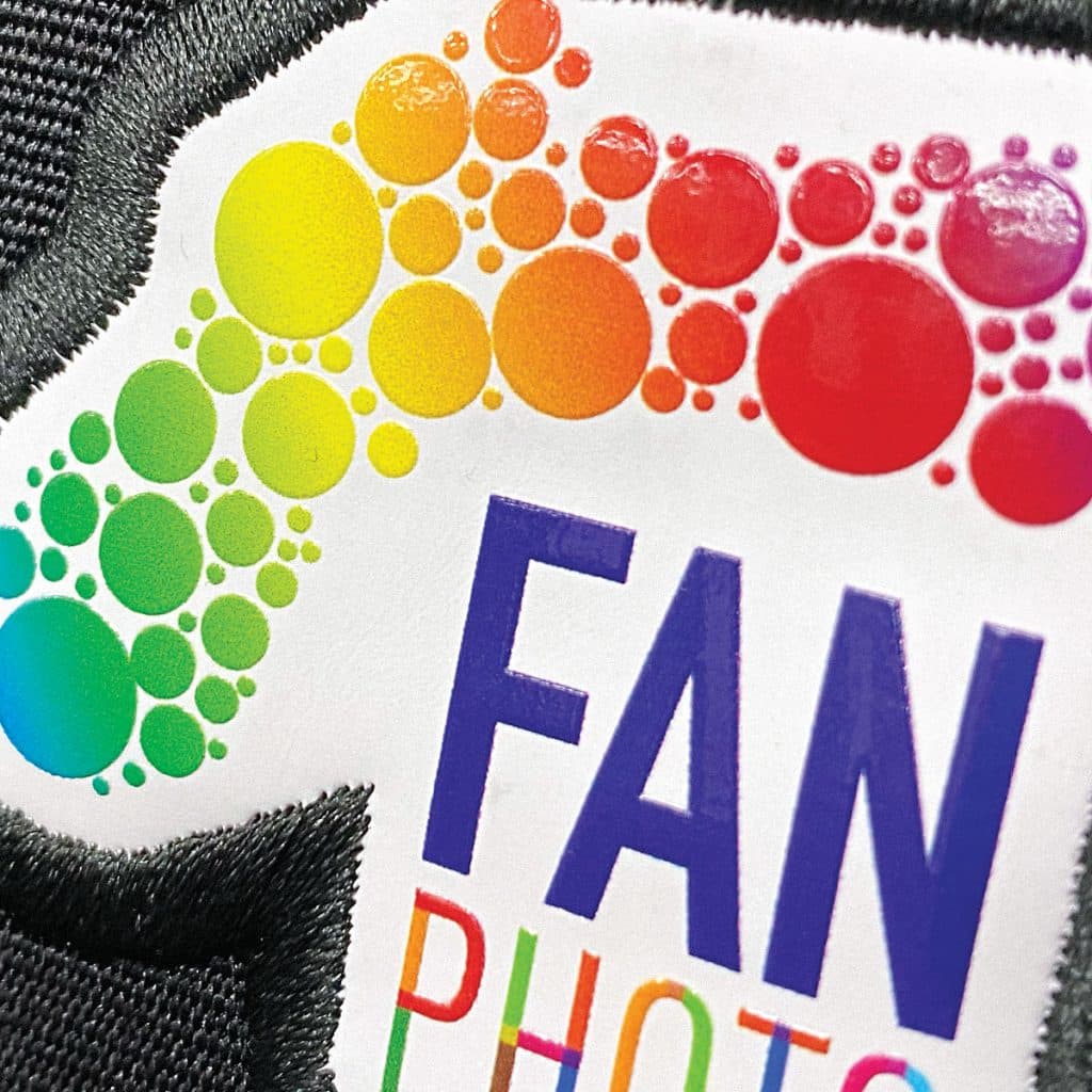 Badge with vibrant, high-resolution fan design on dark fabric, finished with a white stitched border.