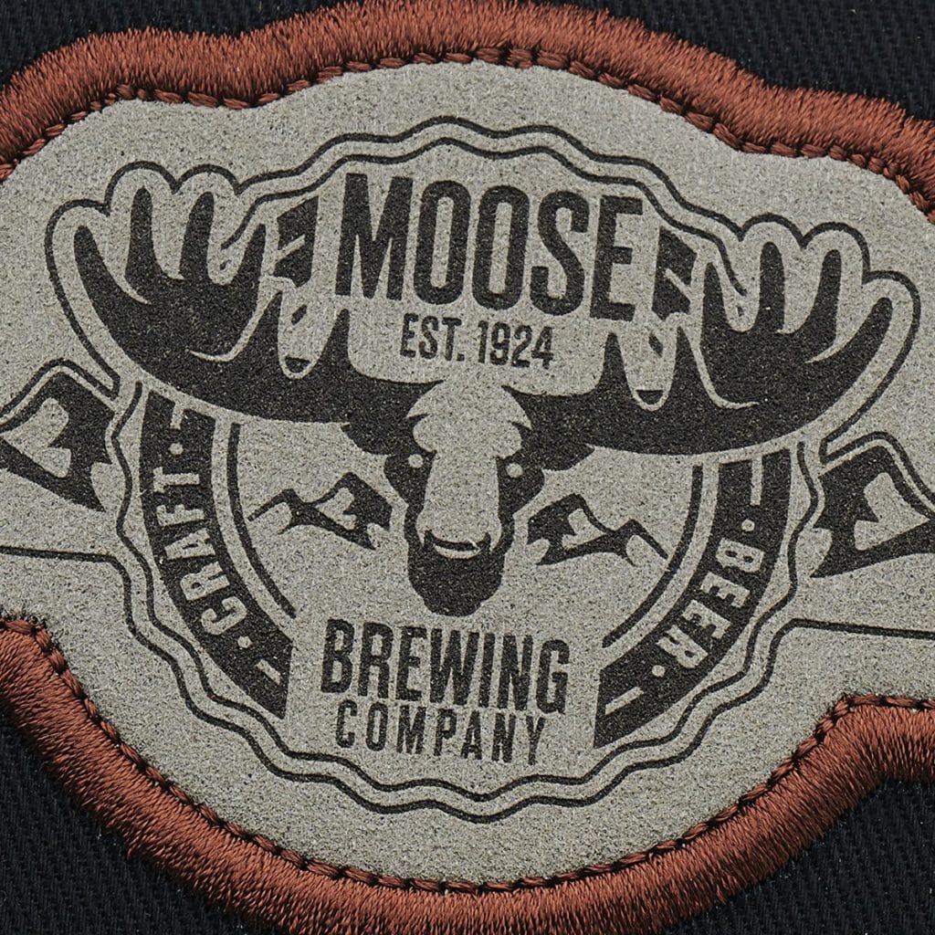 Muted SupaEtch patch in grey suede with brown embroidery framing a vintage-style moose brewing logo.