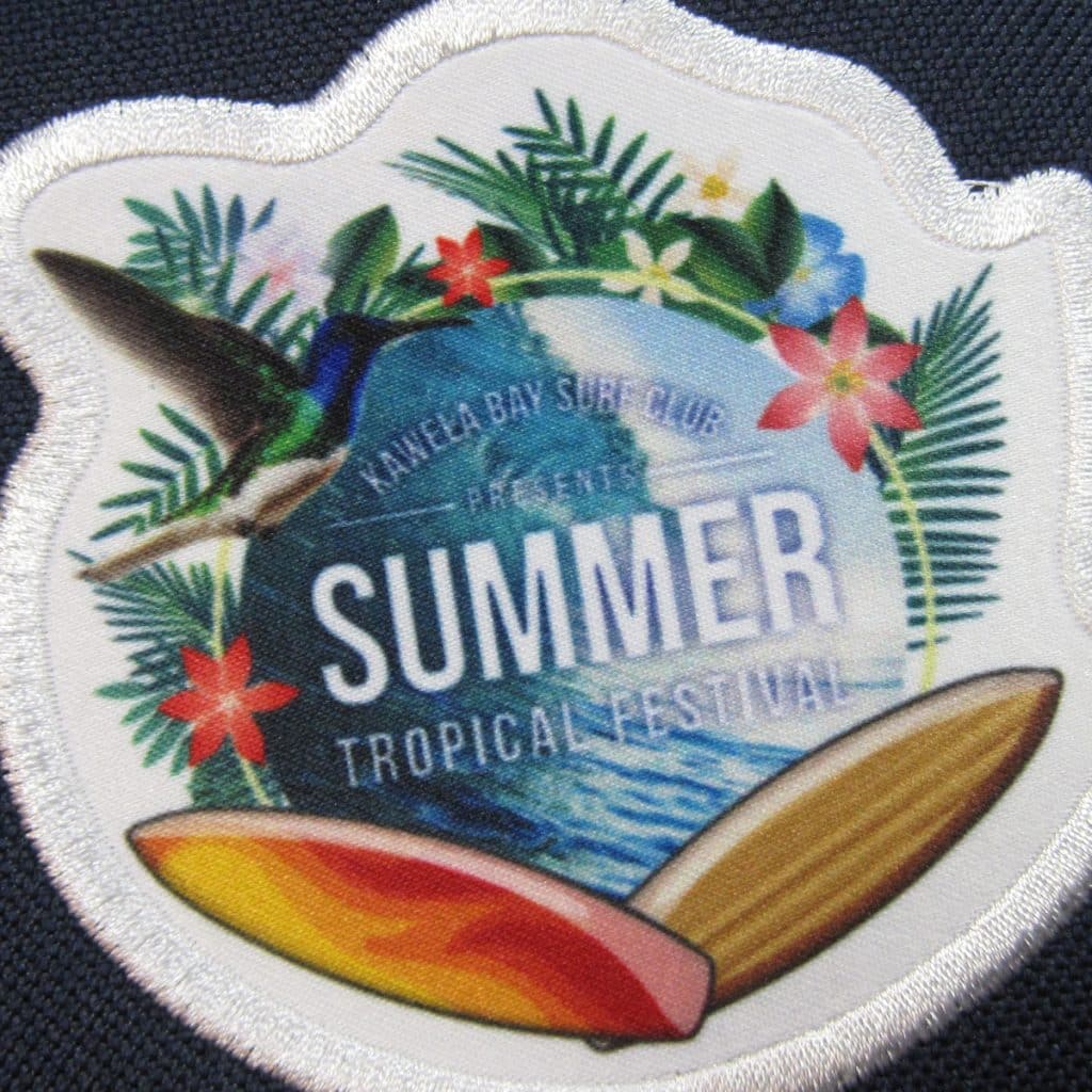 Patch featuring flowers, a hummingbird, surfboards and “Summer Tropical Festival” text, capturing vibrant seasonal best branded merchandise.