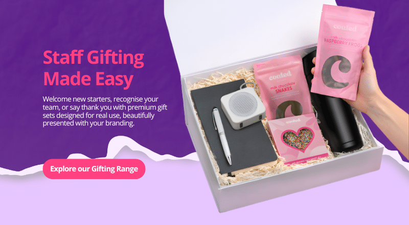 Staff gifting corporate gift box with branded drink bottle, notebook, pen, speaker and gourmet chocolates, promoting premium onboarding and employee gift sets.